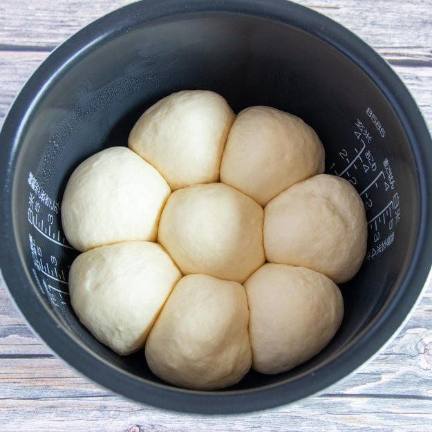 オーブン不要！ 炊飯器でふわっふわのちぎりパン, レシピの基本情報：, 作り方：① 耐熱ボウルに牛乳を入れ、ふんわりとラップをかけて600Wの電子レンジで30秒加熱する。, ② ①にドライイーストを入れて混ぜ合わせる。, ③ 別のボウルに【A】を入れて混ぜ、②を加えてひとまとまりになるまでこねる。バターを加えてさらにこね、表面が張るように丸める。, ④ ふんわりとラップをかけ、2倍の大きさになるまで1時間ほどおく。, ⑤ ④をこぶしで押してガスを抜き、8等分にして表面が張るように丸める。内釜に並べてふたをし、1.5倍の大きさになるまで40分ほどおく。, ⑥ きな粉と砂糖を混ぜたものを⑤に茶こしで振りかけ、通常通り炊飯する。炊き上がったらすぐに内釜から取り出し、粗熱がとれたら、完成！