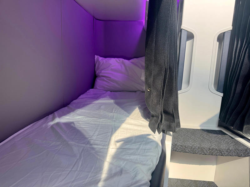 I'd book the Skynest to fight jet lag. The Skynest will be located in the middle of the plane., It features curtains, power, and a seatbelt., Flyers get soft linens and an amenity kit., I'd prefer the bottom or middle bunks., Flyers will eat before or after their block., You must be 15 or older., I'd book the Skynest to fight jet lag., The Skynest is ANZ's second economy bed.