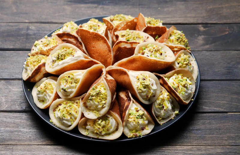 24. Qatayef, Middle East 61. Rigó Jancsi, Hungary, 60. Sorbet, various locations, 59. Sticky rice with mango, Thailand, 58. Ma’amoul, Egypt, 57. M’hanncha, Morocco, 56. Vermicelles, France, Italy and Switzerland, 55. Thapthim krop, Thailand, 54. S’mores, USA, 53. Dadar gulung, Indonesia, 52. Cannoli, Italy, 51. Crème caramel, France, 50. Rum cake, Caribbean, 49. Torrijas, Spain, 48. Malva pudding, South Africa, 47. Koeksister, South Africa, 46. Carlota de limón, Mexico, 45. Banoffee pie, England, UK, 44. Alfajores, South America, 43. Doughnuts, various locations, 42. Medovik, Russia, 41. Crumble, UK, 40. Lamington, Australia, 39. Bread and butter pudding, England, UK, 38. Profiteroles, France, 37. Galaktoboureko, various locations, 36. Gelato, Italy, 35. Churros, Spain and Portugal, 34. Gulab jamun, India, 33. Trifle, England, UK, 32. Snow ice, Taiwan, 31. Red velvet cake, USA, 30. Crêpes Suzette, France, 29. Bienenstich, Germany, 28. Chocolate soufflé, France, 27. Baked Alaska, USA, 26. Mooncakes, China, 25. Panna cotta, Italy, 24. Qatayef, Middle East, 23. Eton mess, England, UK, 22. Pecan pie, USA, 21. Pavlova, Australia or New Zealand, 20. Brownies, USA, 19. Rote grütze, Germany, 18. Tarte Tatin, France, 17. Kulfi, India, 16. Tiramisù, Italy, 15. Crème brûlée, France, 14. Frozen yogurt, USA, 13. Sticky toffee pudding, UK, 12. Black Forest gâteau, Germany, 11. Nanaimo bar, Canada, 10. Cendol, Southeast Asia, 9. Mochi, Japan, 8. Tres leches cake, Latin America, 7. Baklava, Türkiye, 6. Key lime pie, USA, 5. Chocolate mousse, France, 4. Apfelstrudel, Austria, 3. Apple pie, various locations, 2. Cheesecake, various locations
