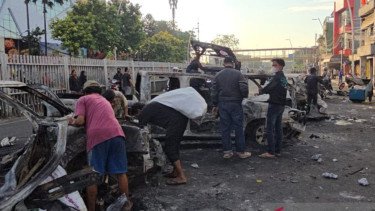 Sejumlah orang mempereteli bangkai mobil yang terbakar di depan Polres Jaktim