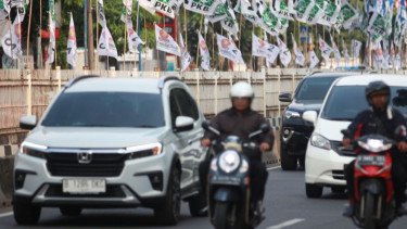 Pengendara melintas dekat bendera parpol yang dipasang