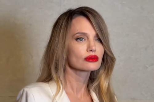 Rambut pirang dengan nuansa lebih modern, Lipstik merah tetap jadi identitas, Wrap coat putih tampilkan kesan mewah yang tenang, Gaya minimalis yang terasa kuat dan berkelas, Penampilan langka yang selalu mencuri perhatian, Angelina Jolie Tampil Beda di Shanghai, Rambut Pirang dan Lipstik Merah Jadi Sorotan