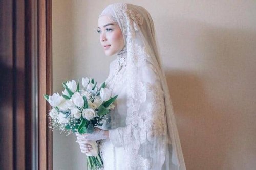 1. Tampil manis dengan kebaya khas Sunda yang sederhana. Lengkap dengan siger atau mahkota pernikahan khas adat Sunda., 2. Dress putih model brokat yang simpel bisa jadi pilihan untuk kamu yang anti ribet. Supaya lebih spesial, tambahkan aksesori di atas kepala dengan veil yang anggun., 3. Jangan ragu coba pakai kebaya model off-shoulder di hari pernikahan. Detail pearl pada kebaya dijamin membuat penampilan jadi lebih maksimal., 4. Bergaya a la putri keraton Yogyakarta dengan kebaya adat Jawa yang anggun. Andalkan kebaya klasik model kutubaru dengan aksen bordir yang menutupi bagian pundak., 5. Lace dress dengan dasar warna putih memang tidak pernah gagal untuk baju akad nikah yang elegan. Makin sempurna dengan hiasan kepala berupa tudung pernikahan yang seragam dengan bahan gaun., Inspirasi Baju Akad Nikah yang Simpel dan Elegan