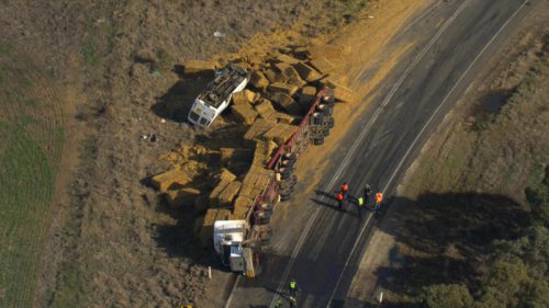 Driver airlifted to hospital after school bus flips in collision with hay truck