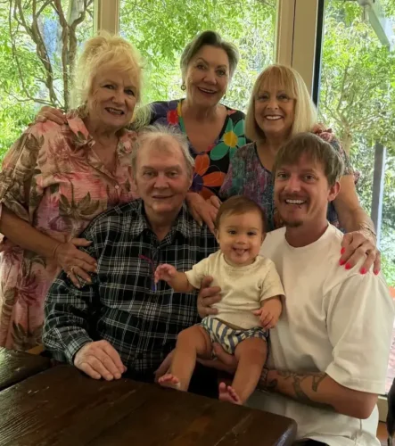 Smiles all round: John Farnham makes rare appearance at family gathering with close friend Denise Drysdale following cancer battle