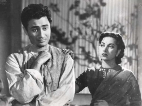 Long before Bollywood became obsessed with celebrity relationships, there was a real-life love story that captivated an entire generation. It involved two of Hindi cinema's biggest stars, secret meetings, handwritten notes, family opposition, and a romance so intense that it remained unforgettable decades later. The love story of Dev Anand and Suraiya wasn't just another film-industry affair. It was the kind of romance that seemed destined for a happy ending, until reality intervened. (File Photo), In the late 1940s, Suraiya was already one of the biggest names in Indian cinema. She was not only a successful actress but also a hugely popular singer whose fame often eclipsed that of her male co-stars. Dev Anand, on the other hand, was still finding his footing in the industry. (File Photo), They reportedly fell in love while working together on the 1948 film Vidya. According to popular accounts, Dev Anand even saved Suraiya from drowning when their boat overturned during a shooting sequence. Whether that moment sparked their romance or simply brought them closer, the two soon became inseparable. Over the next few years, they appeared together in several films and became one of the most adored on-screen pairs of their era. (File Photo), In his autobiography Romancing With Life, Dev Anand revealed just how deeply he loved Suraiya. One of the most touching moments came when Suraiya responded to one of his letters. "I cried as I read your letter. It is mutual. I love you. I, too, am dying to meet you," she reportedly wrote. But theirs was not an easy romance. In later interviews, Suraiya claimed her grandmother and maternal uncle threatened Dev Anand and pressured her to end the relationship because he was Hindu while she came from a conservative Muslim family. (File Photo), Suraiya's family, particularly her maternal grandmother, strongly opposed the relationship. Dev wrote about making secret phone calls, arranging hidden meetings, and finding ways to communicate despite constant surveillance. One late-night terrace meeting became one of the most famous chapters of their love story. According to Dev Anand's account, he finally met Suraiya after days of separation, embraced her, and proposed marriage. "Will you marry me?" he asked. Suraiya's response was simple but unforgettable: "I love you! I love you! I love you!" (File Photo), Certain that they would marry, Dev Anand bought an expensive engagement ring for Suraiya. The actress reportedly treasured it and accepted it privately. For a brief moment, it seemed like love had won. But family pressure continued to intensify. According to several accounts, Suraiya's grandmother was firmly against the relationship because of religious differences and reportedly threatened severe consequences if the couple went ahead with the marriage. Eventually, the pressure became too much. (File Photo), The romance that once seemed unstoppable slowly began to collapse. Dev Anand later revealed that Suraiya stopped communicating with him. The actress was allegedly forced to distance herself from him and swear that she would end the relationship. One of the most tragic details from their story involves the engagement ring. According to accounts shared later, Suraiya eventually threw the ring into the sea, a symbolic end to a love she could not fight for. (File Photo), Years later, Suraiya herself reflected on the painful decision. "The reasons were many. But the most important was that though I was sure of Dev's love, I was unsure of myself. I was confused," she reportedly told Stardust. When she refused to marry him, Dev Anand reportedly called her a "coward." "Maybe I was one. I admit I was not absolutely sure. Perhaps it was a folly, perhaps a mistake or perhaps destiny?" she said. (File Photo), Dev Anand eventually moved on and married actress Kalpana Kartik in 1954. Yet he never hesitated to acknowledge the impact Suraiya had on his life. "Yes. I loved Suraiya," he said years later. "It was a very important chapter of my life. I was young and in love for the first time." He also admitted that had he married her, his life might have taken a completely different course. Suraiya, meanwhile, never married. (File Photo), She was a superstar, he was a rising hero, they fell in love on set, but one heartbreaking choice changed everything